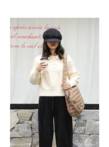 Detailed lifestyle shot of a model wearing a beige quilted nylon grid crossbody bag