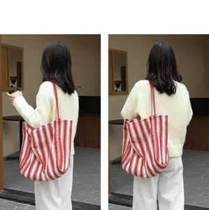 Vista posteriore di una borsa shopping in tela a righe rosse e bianche indossata da modella.