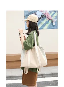 Mujer con bolso tote de lona en color crema y azul claro en un entorno urbano.