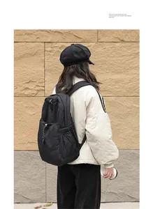 Mochila casual de nailon negro con cordón y diseño plisado mostrada en una persona al aire libre