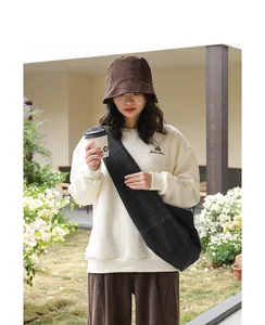 Asian model styling a black denim crossbody dumpling bag in a casual outdoor setting