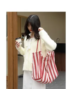 Borsa tote casual in tela a righe rosse e bianche indossata da una modella in un caffè