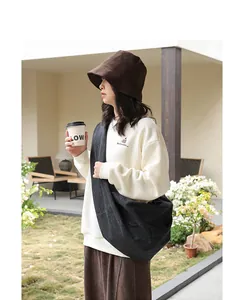 Large black denim crescent crossbody bag shown on a model in a natural garden setting