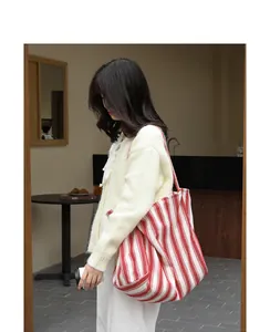 Grande borsa tote in tela a righe bianche e rosse in un contesto lifestyle casual e chic