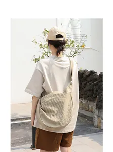 Vista trasera de una persona con un bolso bandolera de lona a cuadros beige al aire libre