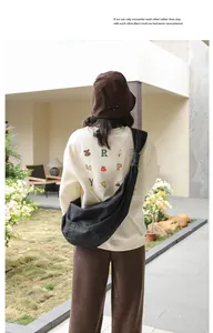 Dark grey denim dumpling bag with a knotted strap worn as a stylish crossbody bag