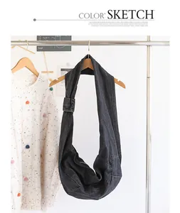 Detail view of dark grey denim dumpling bag with knot strap hanging on clothes rack.