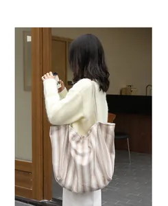 Grande borsa tote in tela a righe sulla spalla di una donna, in stile giapponese.