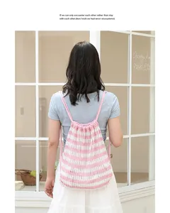 Vista trasera de una chica con una mochila de punto a rayas rosas y blancas fuera.