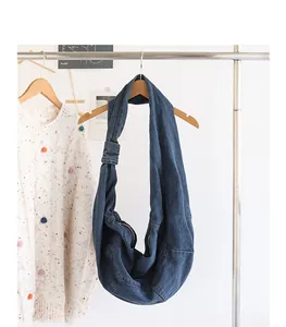 Side view of a stylish blue denim dumpling bag featuring a shoulder knot detail