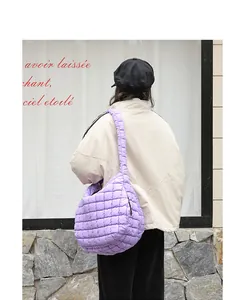 Close-up detail of purple quilted nylon shoulder bag carried by model in street setting