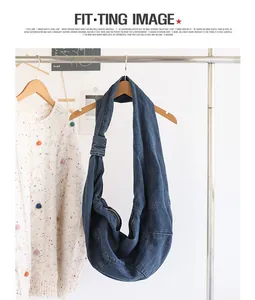 Detailed shot of a stylish blue denim dumpling bag with a knotted strap on a hanger.