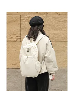 Vista posterior detallada de una mochila de nailon beige de estilo japonés llevada por un modelo.