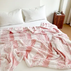 Detailed view of a soft pink and white checkered flannel fleece blanket on a cozy bed.