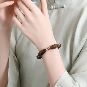 Detailaufnahme eines traditionellen Sandelholz-Armbands mit Kristallperle am Handgelenk