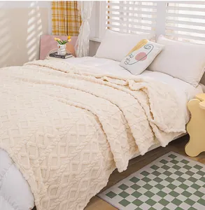 Close-up of cozy cream coral fleece blanket with textured diamond pattern on a bed
