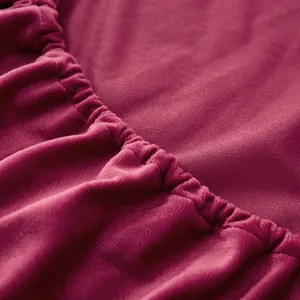 Close-up detail of soft deep pink crystal velvet fitted bed sheet with elasticated hem