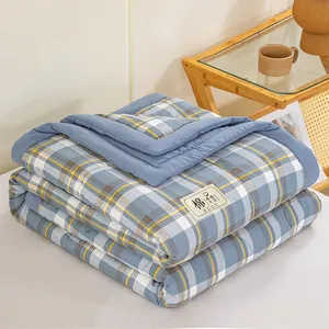 Folded blue and yellow checkered cotton summer quilt on a bed in a minimalist home setting