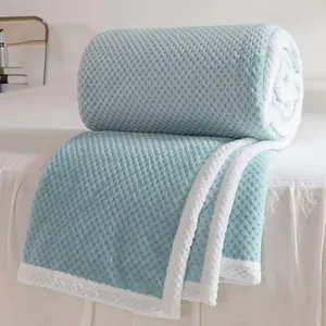 Manta de forro polar verde menta con diseño de rejilla y ribete blanco en una cama