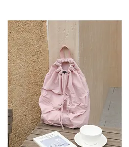 Rosa Nylon-Rucksack mit Kordelzug und zwei Fronttaschen auf einem Holztisch.