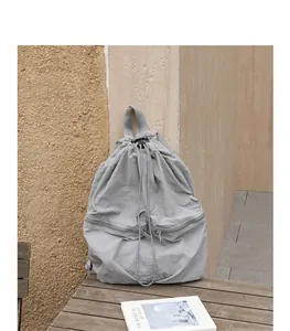 Detailansicht eines hellgrauen Nylon-Rucksacks mit Kordelzug und Faltenstruktur