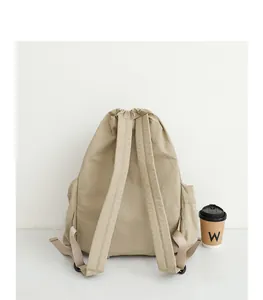 Vista trasera de una mochila beige de nailon con cordón y correas acolchadas ajustables