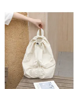 Hand hält einen stilvollen beigen Rucksack mit Kordelzug über einem Holztisch
