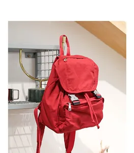 Vista detallada de una mochila de lona roja colgada en un estante de un interior.