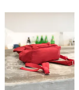 Detalle del fondo y las correas ajustables de una mochila de lona de algodón rojo lavado