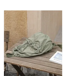 Detailansicht eines grünen Nylon-Rucksacks mit Kordelzug auf einem Holztisch.