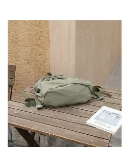 Nahaufnahme eines olivgrünen Nylon-Rucksacks mit Kordelzug auf einem rustikalen Holztisch