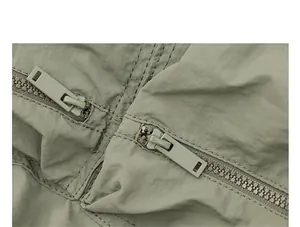 Detailaufnahme der robusten Reißverschlüsse und des Nylonstoffs des salbeigrünen Rucksacks.