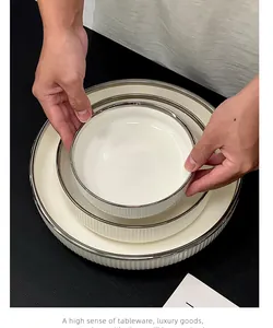 Vue détaillée d'élégantes assiettes en céramique nervurées blanches avec bords argentés en ensemble