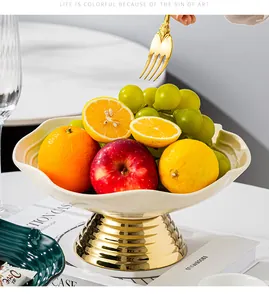 Close-up of modern ceramic pedestal fruit bowl with elegant gold base and fresh fruits
