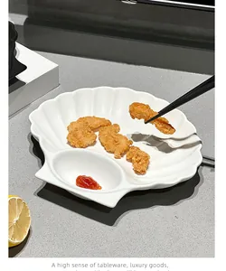 White shell-shaped ceramic plate with a dipping compartment holding crispy fried food