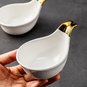 Elegant white ceramic sauce dish featuring a unique gold bird head handle for snacks
