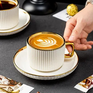 Elegantes weißes Kaffeetassen-Set aus Keramik mit Goldrand und vertikalen Streifen.