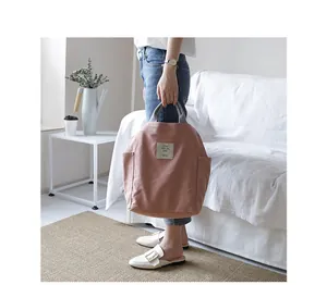 Stylish pink canvas tote bag held by a model in a cozy minimalist home interior.