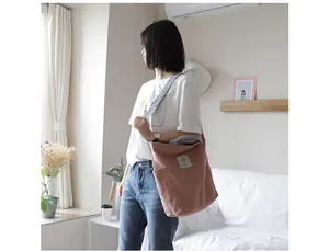 Lifestyle shot of a minimalist pink canvas shoulder bag worn by a model indoors