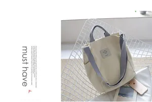 Detailed view of a minimalist cream canvas tote bag with grey straps on a white chair