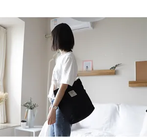 Model wearing a black canvas crossbody bag in a minimalist bright room interior