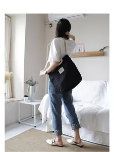 Minimalist black canvas tote bag with large capacity shown in a lifestyle indoor setting