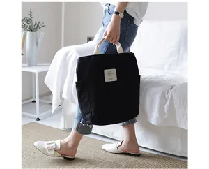 Fashionable model holding a large black canvas tote bag in a bright lifestyle indoor scene