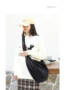 Primer plano de modelo con un bolso bandolera grande de pana negra estilo dumpling informal.