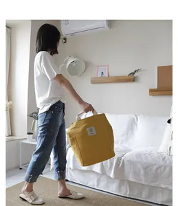 Model holding a large yellow minimalist canvas tote bag in a bright modern living room