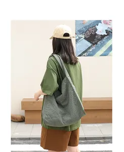 Bolso tote grande de lona a cuadros verdes llevado por una modelo en un ambiente informal.