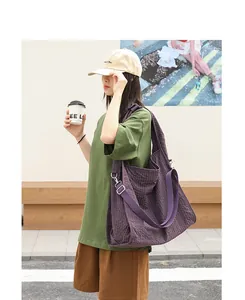 Bolso tote de lona a cuadros morados usado como bandolera por una modelo al aire libre.