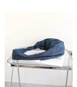 Detail shot of a minimalist blue denim dumpling bag with a knotted shoulder strap