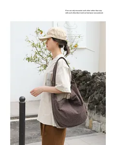 Modelo asiática con un bolso de lona a cuadros marrones en un entorno al aire libre