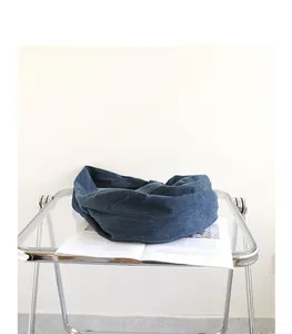 Close-up of a blue denim dumpling bag placed on a transparent glass chair